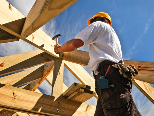 Man using hammer to pound in nails of house roof
