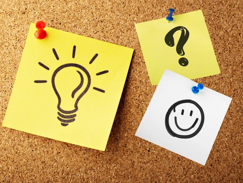 Bulletin board with sticky notes with lightbulb, question mark and smiley face