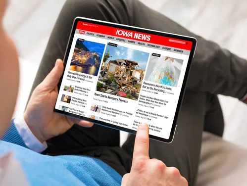 Person holding tablet featuring news stories